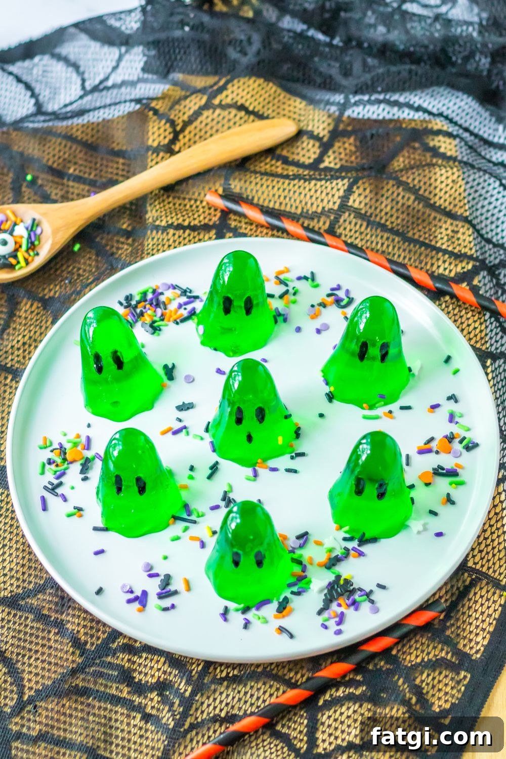 Ghost Jello Shots for Halloween Parties 9 platter with green ghost jello shots on it with a spider web coaster under the platter