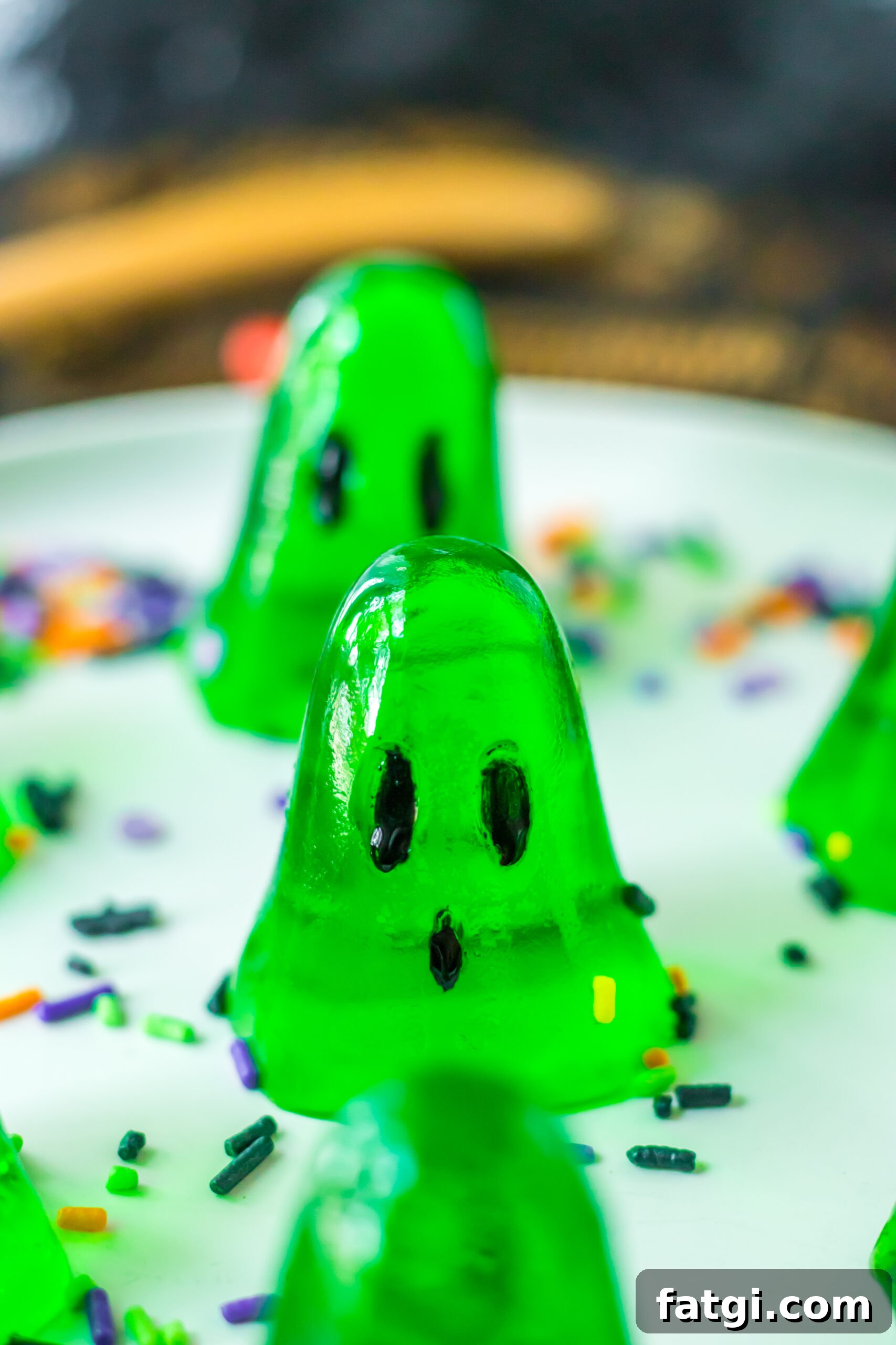 Ghost Jello Shots for Halloween Parties 10 platter with green ghost jello shots on it with a sprinkles on the plate