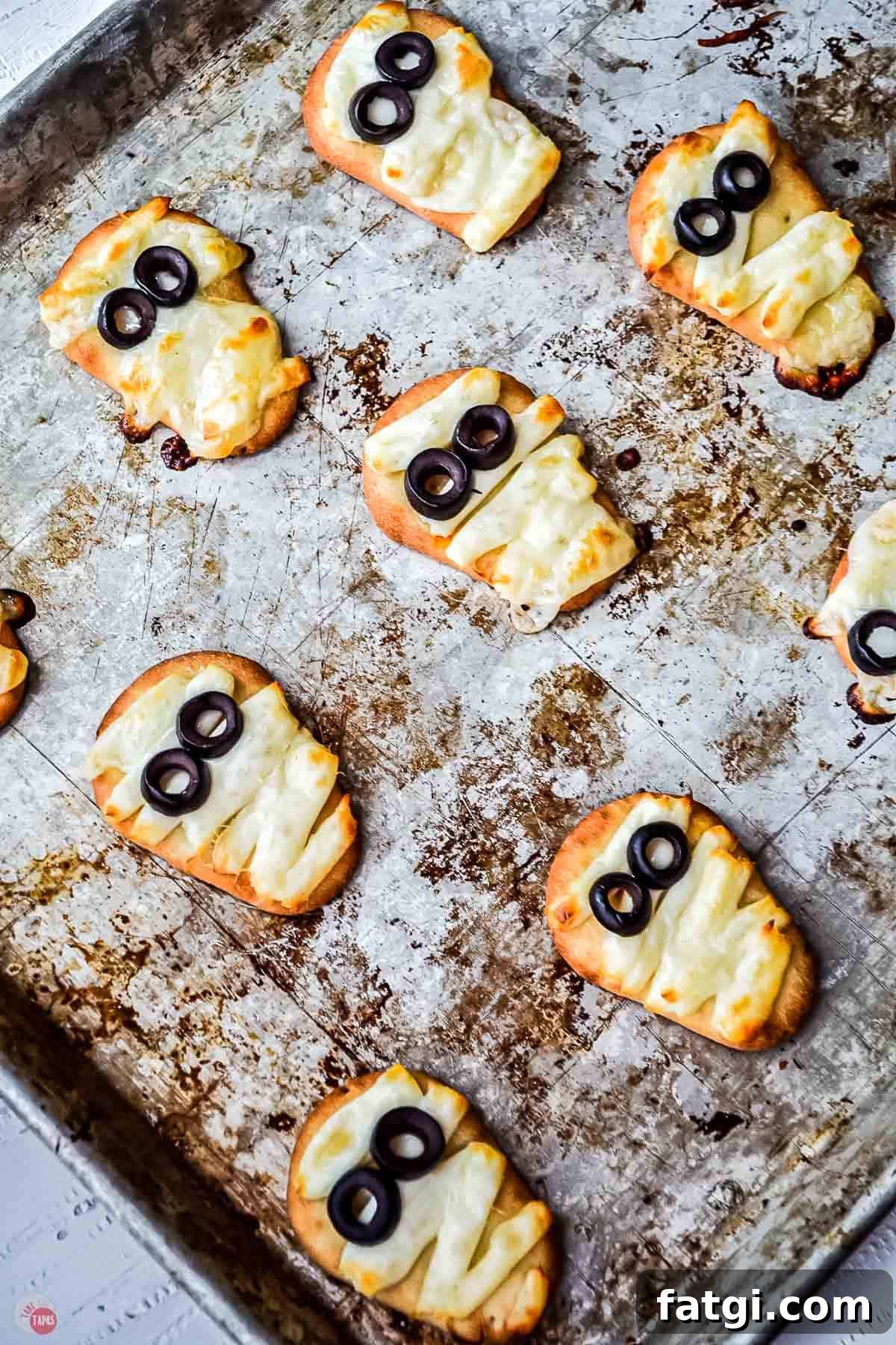 Mini Mummy Pizza Dippers for Halloween 8 baked naan mummies on a baking sheet