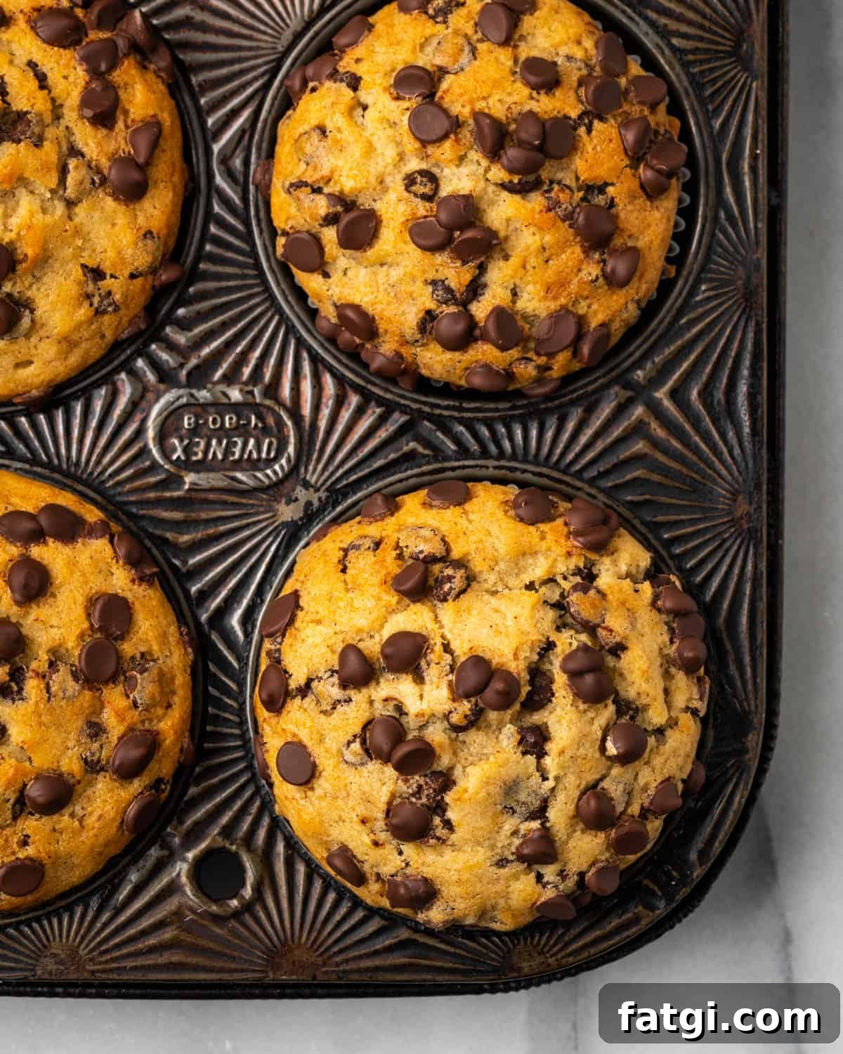 A muffin tin with baked banana chocolate chip muffins.