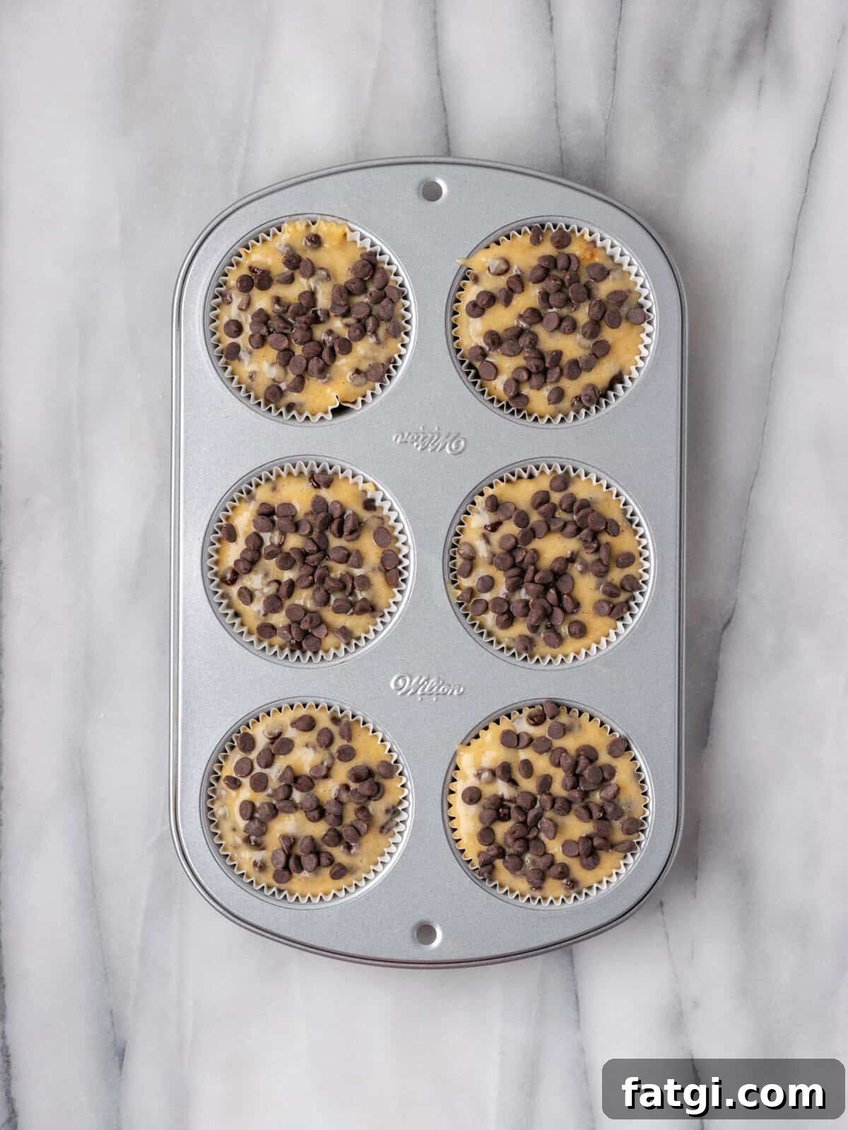 Unbaked gluten free banana chocolate chip muffins in a muffin tin.