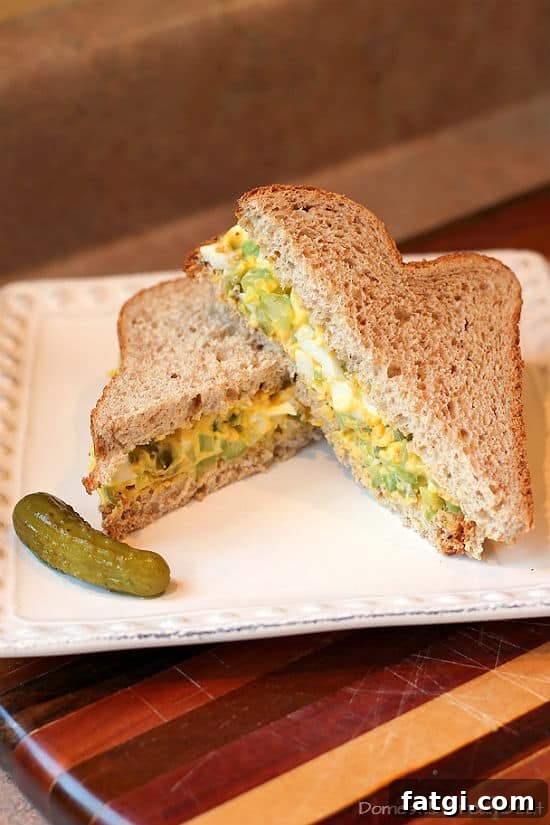 Dill egg salad sandwich cut in half on a white plate.