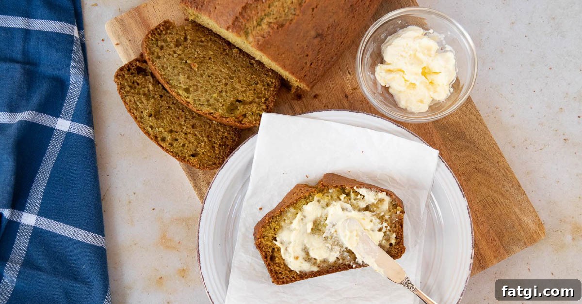 Overhead shot of a loaf of zucchini bread with a slice being spread with clotted cream