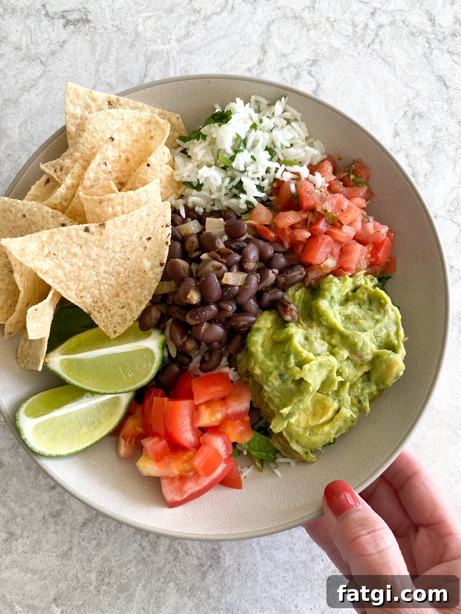 Homemade Chipotle style salad bowl with rice, black beans, guacamole, pico de gallo, lettuce, and tortilla chips