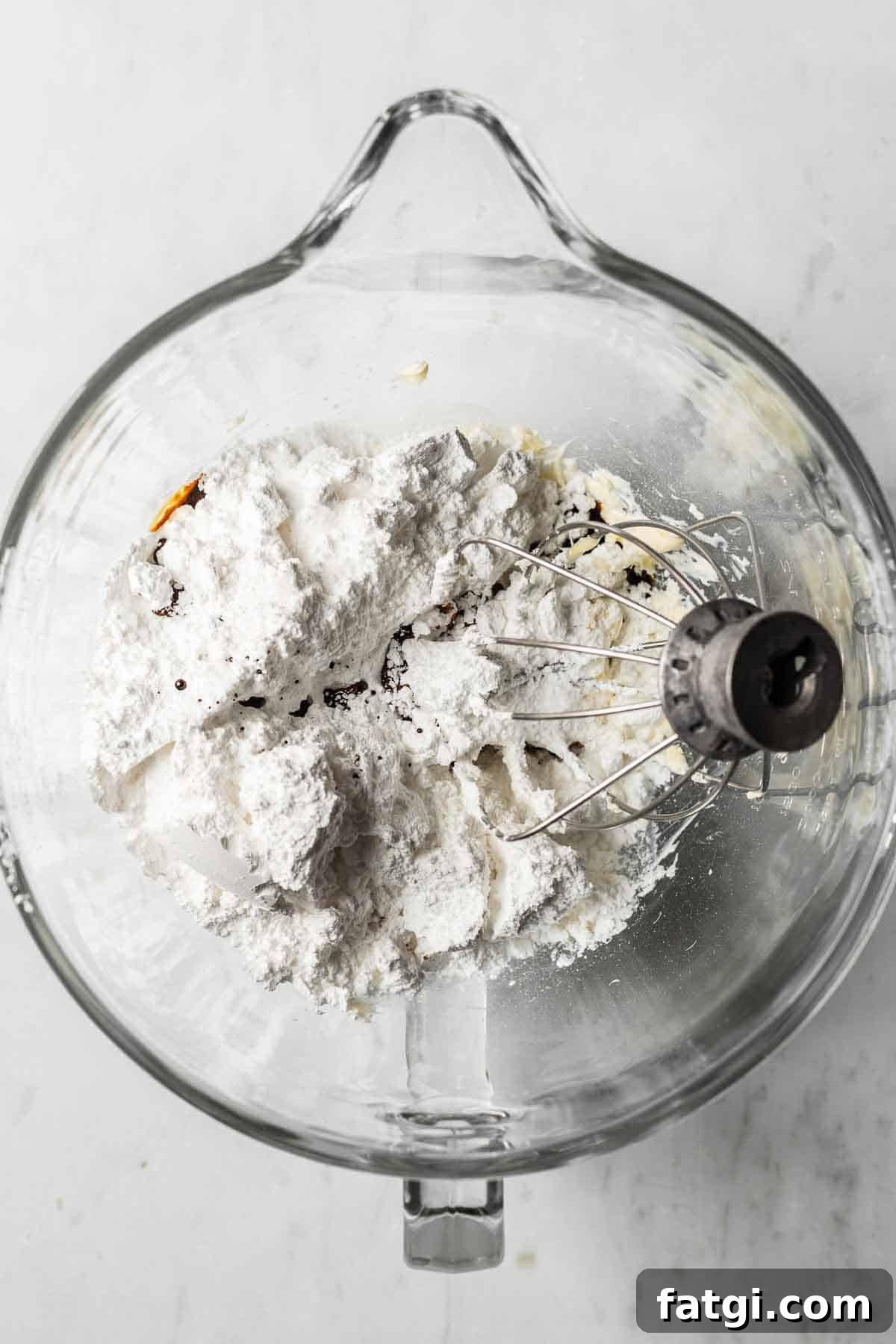Butter, powdered sugar, espresso powder, vanilla and salt in a glass mixing bowl for frosting.