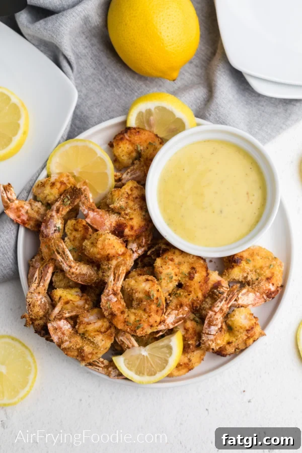 Crispy Keto Air Fryer Fried Shrimp 3 Keto fried shrimp made in the air fryer on a white plate with lemon slices and dipping sauce - ready to serve.
