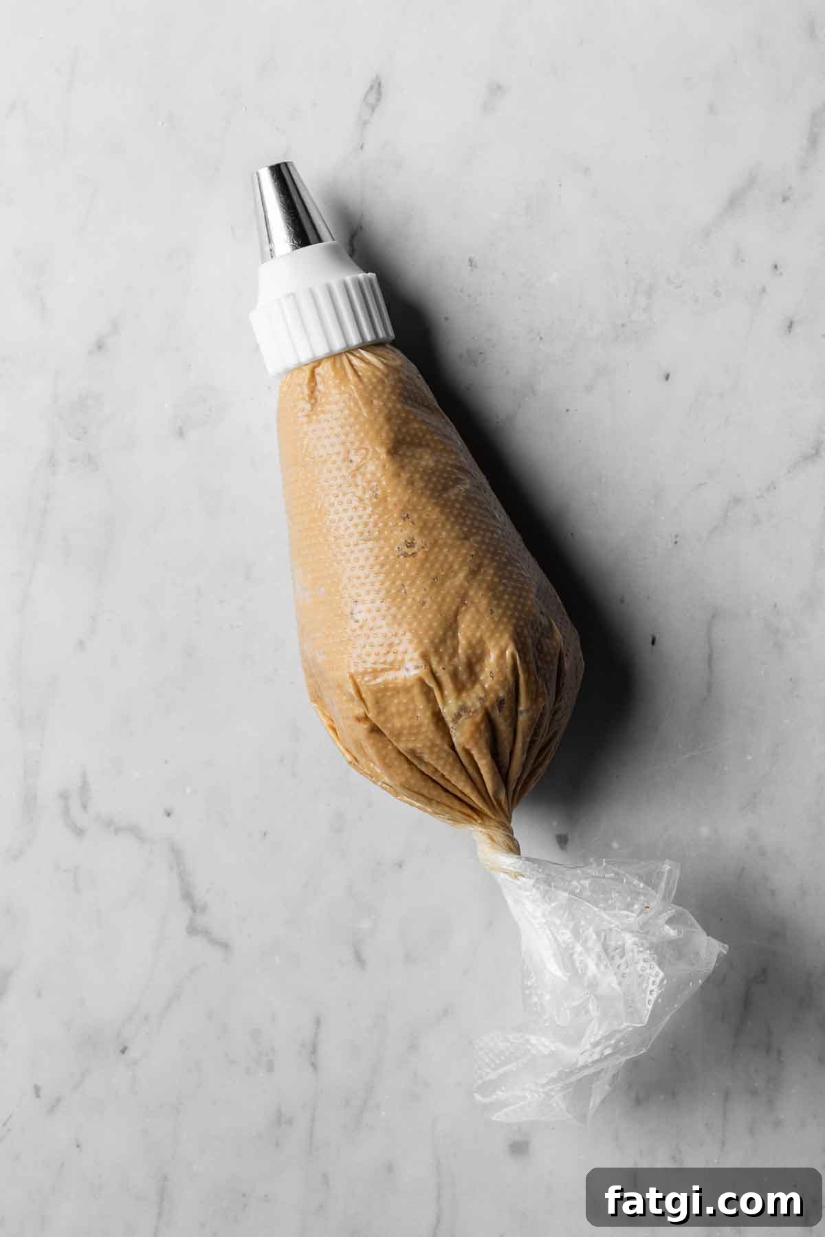 A 16 inch piping bag filled with coffee mascarpone buttercream frosting fitted with a round piping tip.