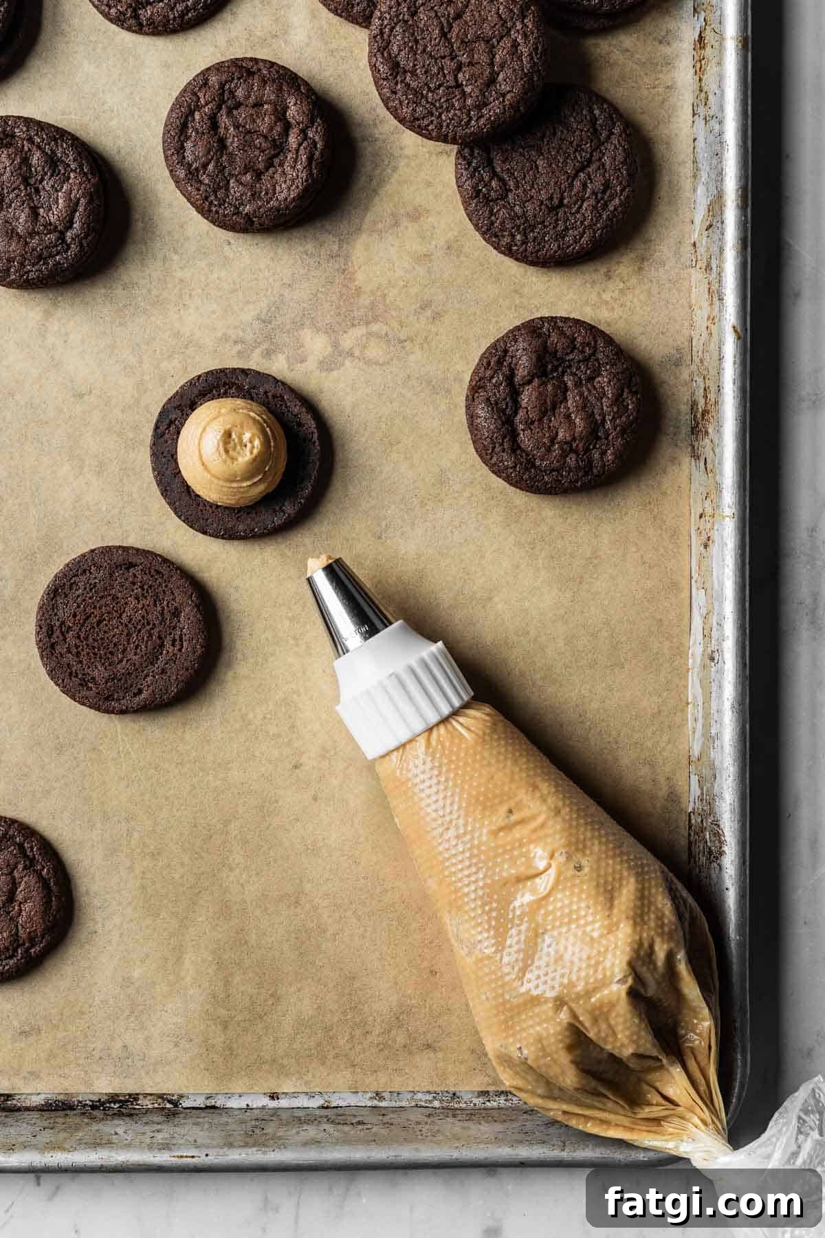 A piping bag of coffee mascarpone frosting and a circle of frosting piped onto a chocolate cookie for sandwich cookies.