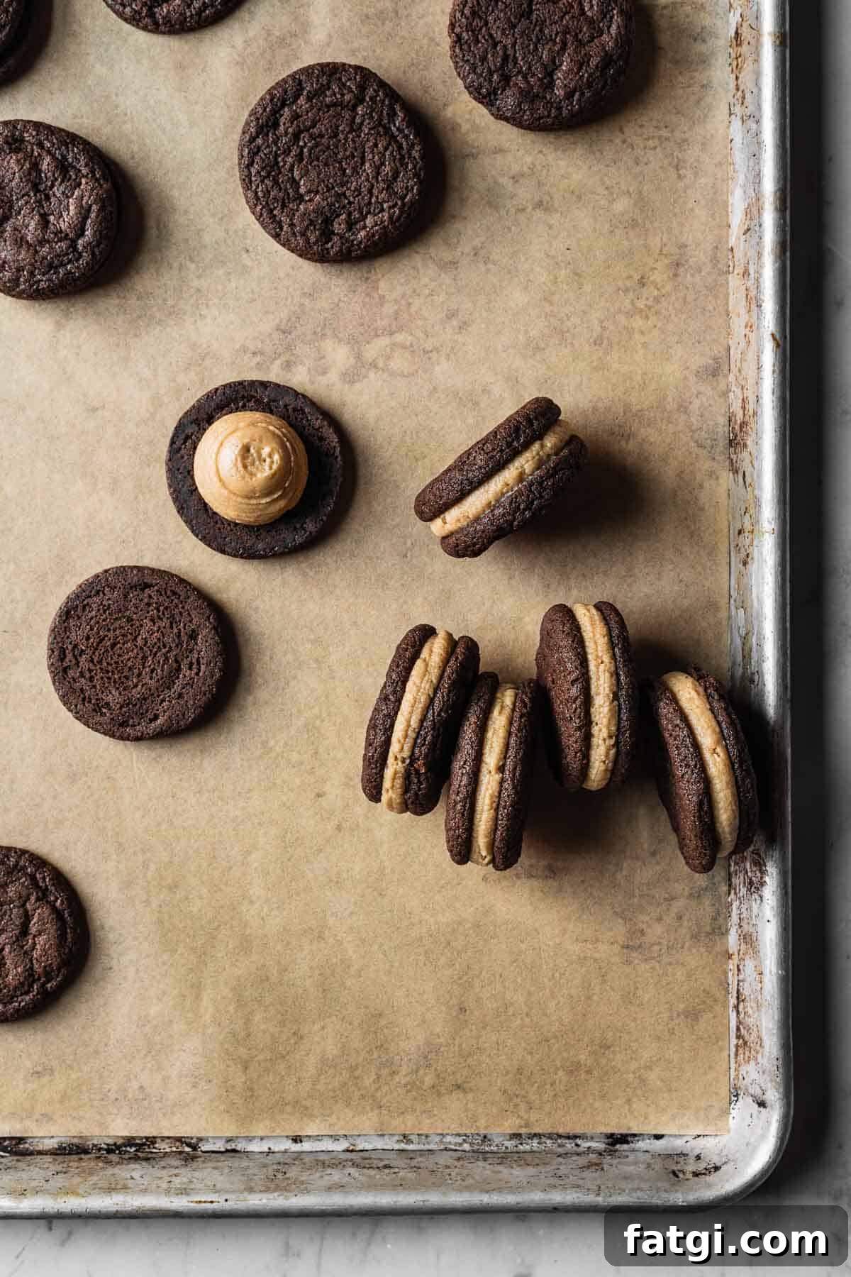 Chocolate cookies filled with coffee mascarpone frosting on a parchment lined baking sheet.