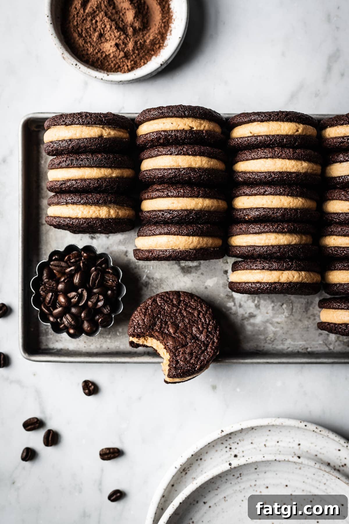 Rows of chocolate coffee mascarpone sandwich cookies on a metal cookie sheet.