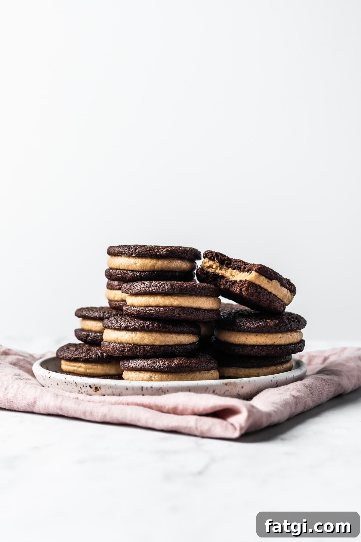 A stack of sandwich cookies on a ceramic plate.