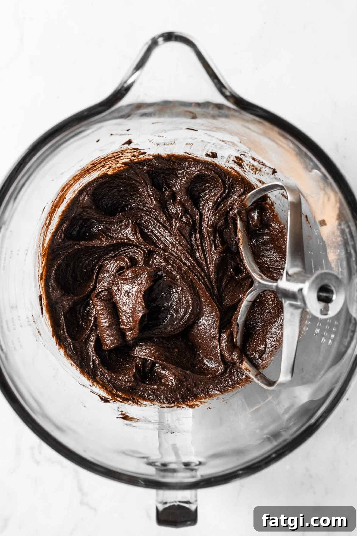 An egg fully mixed into the wet ingredients for chocolate cookie dough.