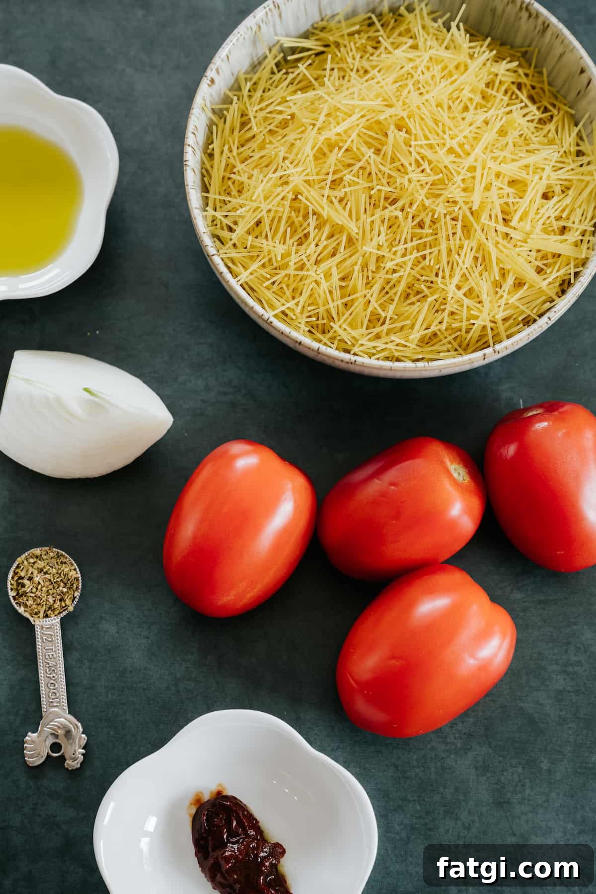 ingredients needed for making Mexican fideo seco pasta laid out on a dark table.
