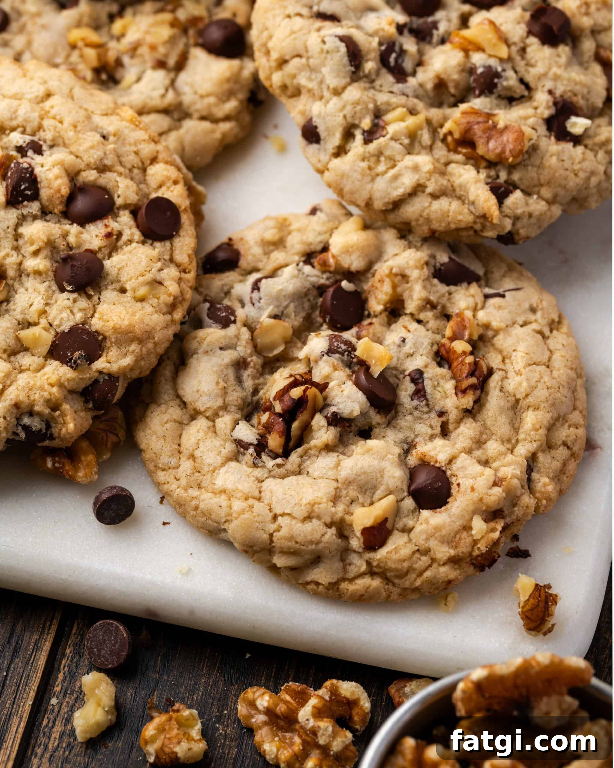 Walnut chocolate chip cookies laying on a marble tray. 