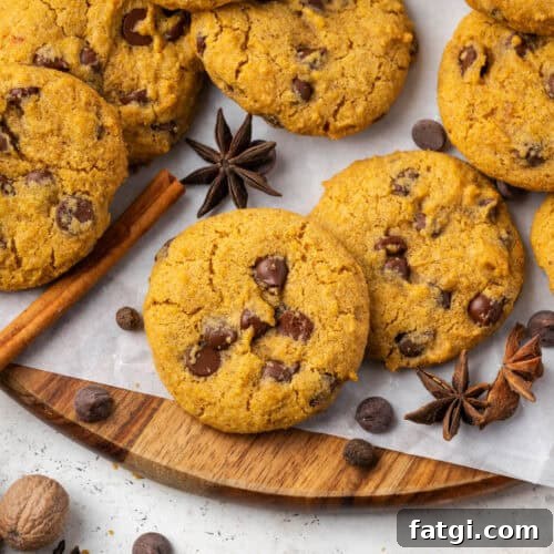 A batch of gluten free pumpkin chocolate chip cookies scattered on a wood tray.