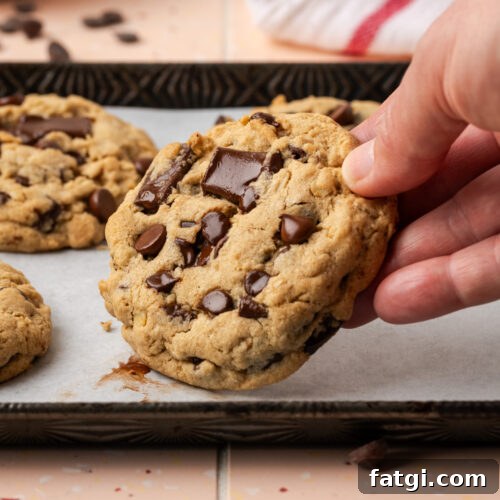 A hand picking up a chocolate chunk cookies off of a baking sheet.