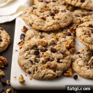A batch of gluten free walnut chocolate chip cookies scattered on a marble serving board.