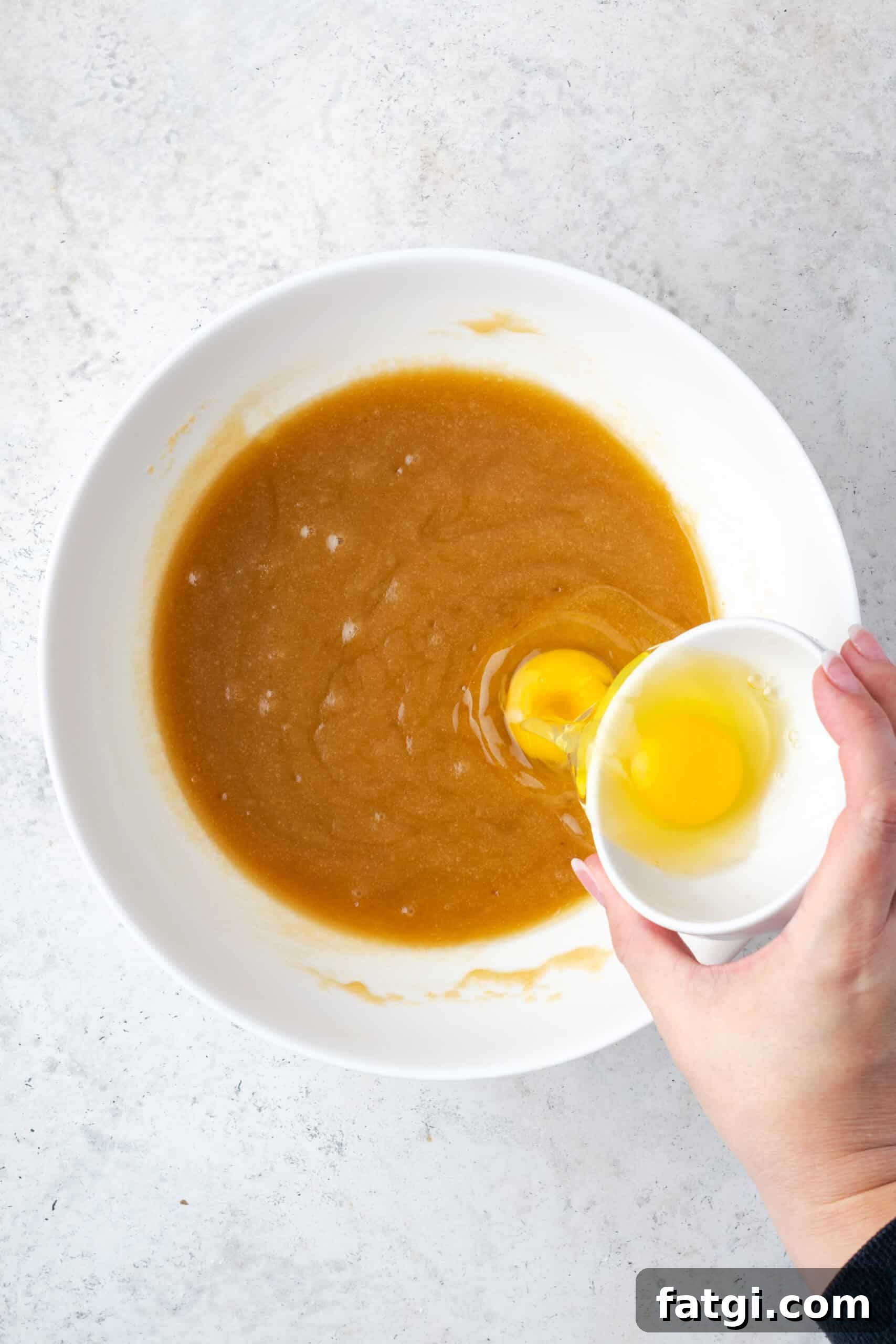 Eggs being added into the bowl with the butter sugar mixture.