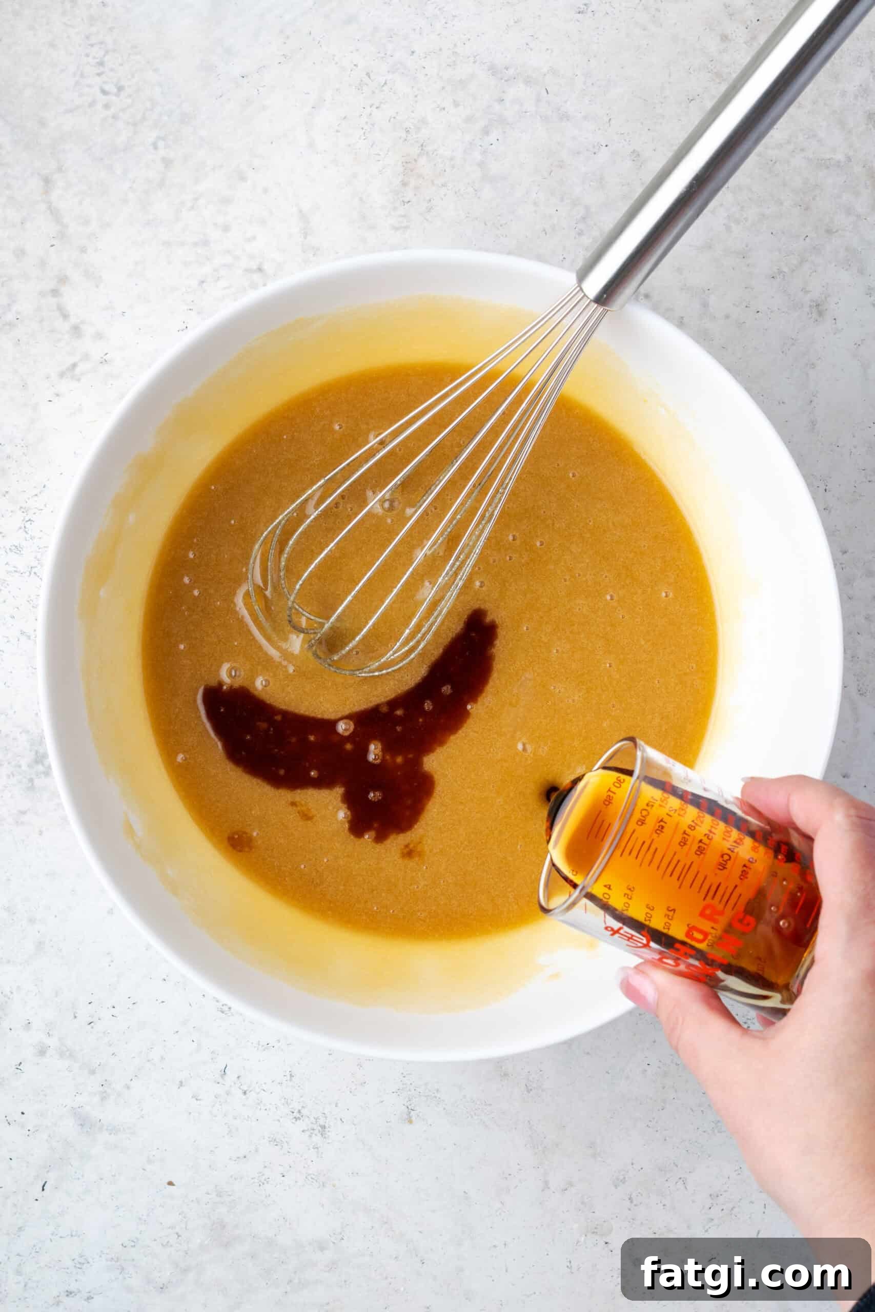 Vanilla and maple syrup being poured into the partially mixed cookie dough.