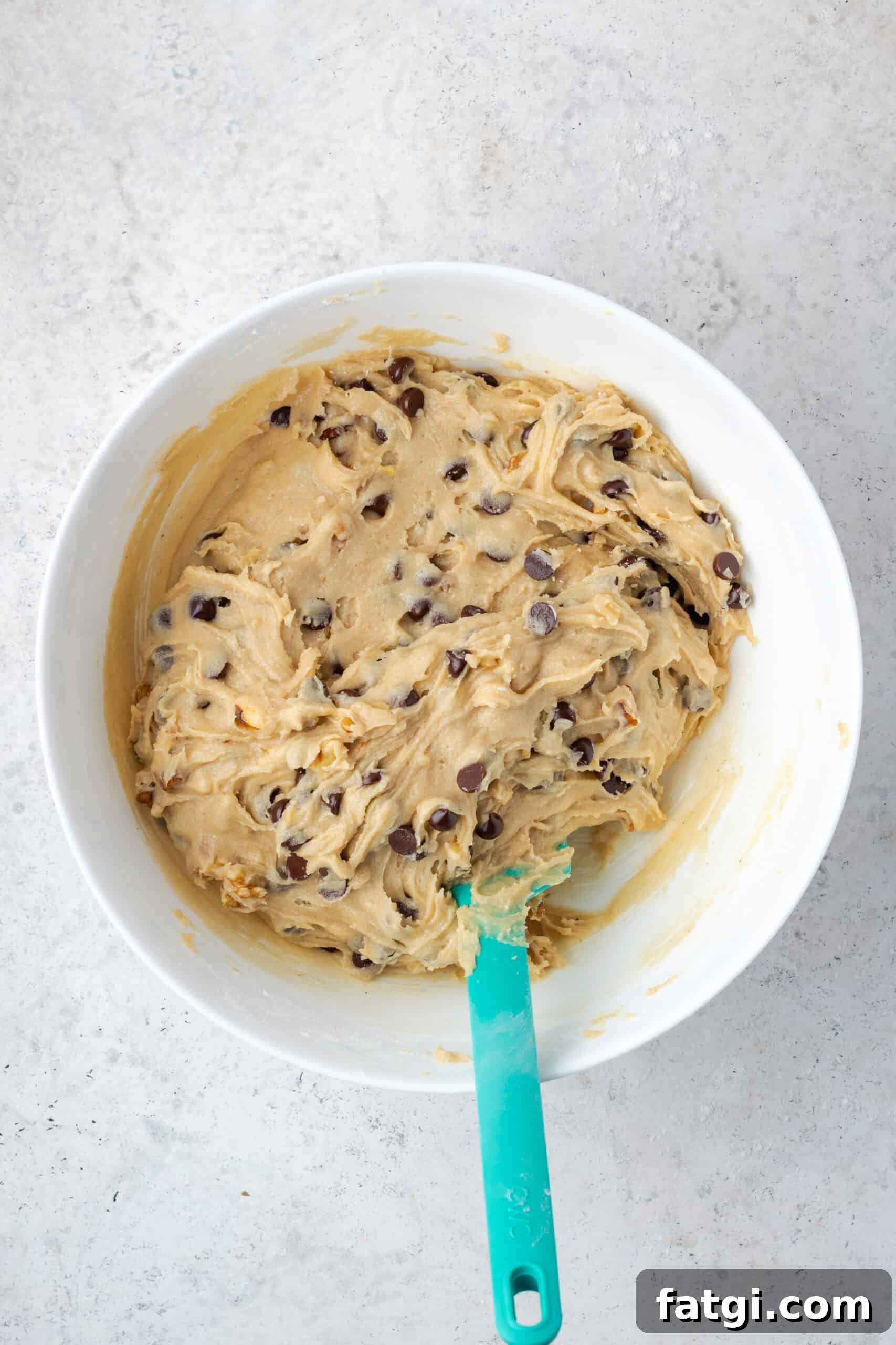 A bowl of walnut chocolate chip cookie dough sitting on a counter.