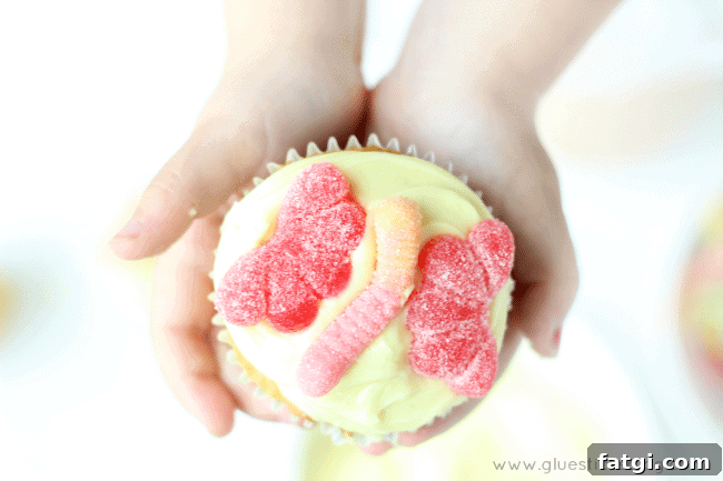 Fun Cake Recipes Kids Can Make at Home 15 Hand holding a butterfly cupcake frosted with yellow frosting.