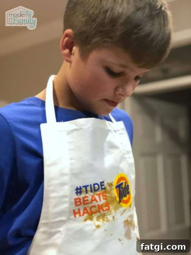 A boy wearing a food stained white apron.