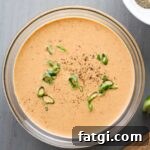 A glass bowl with creamy chipotle lime sauce topped with fresh scallions.