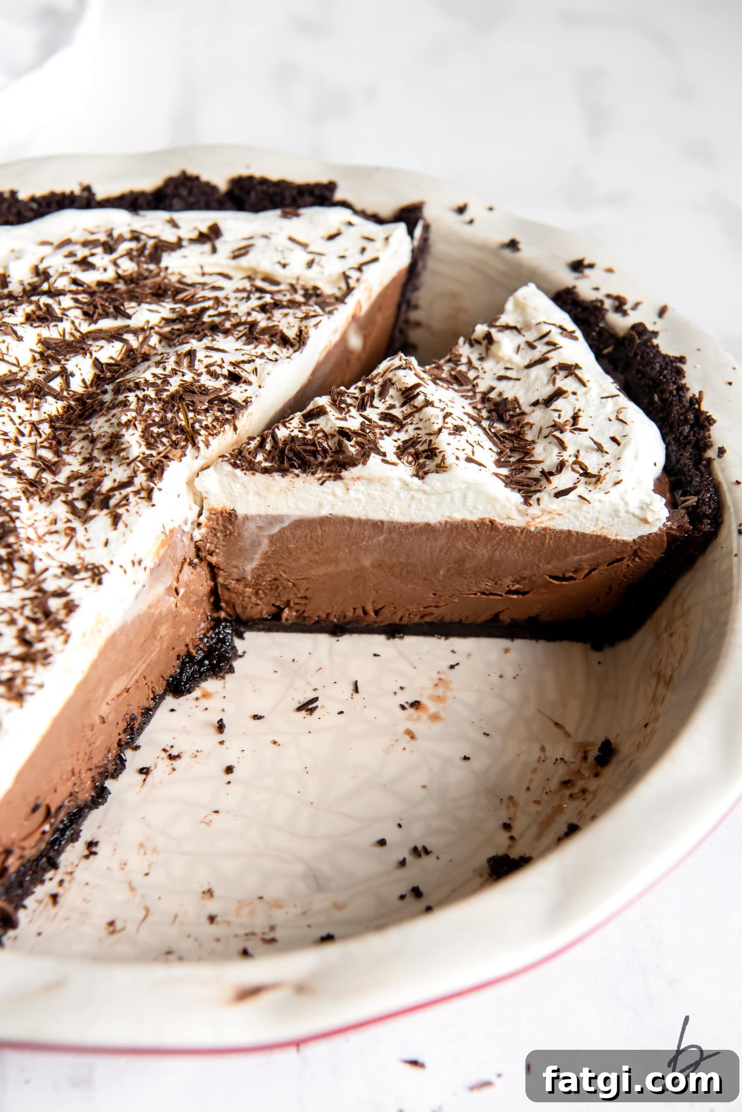 chocolate cream pie slice in pie plate next to rest of pie