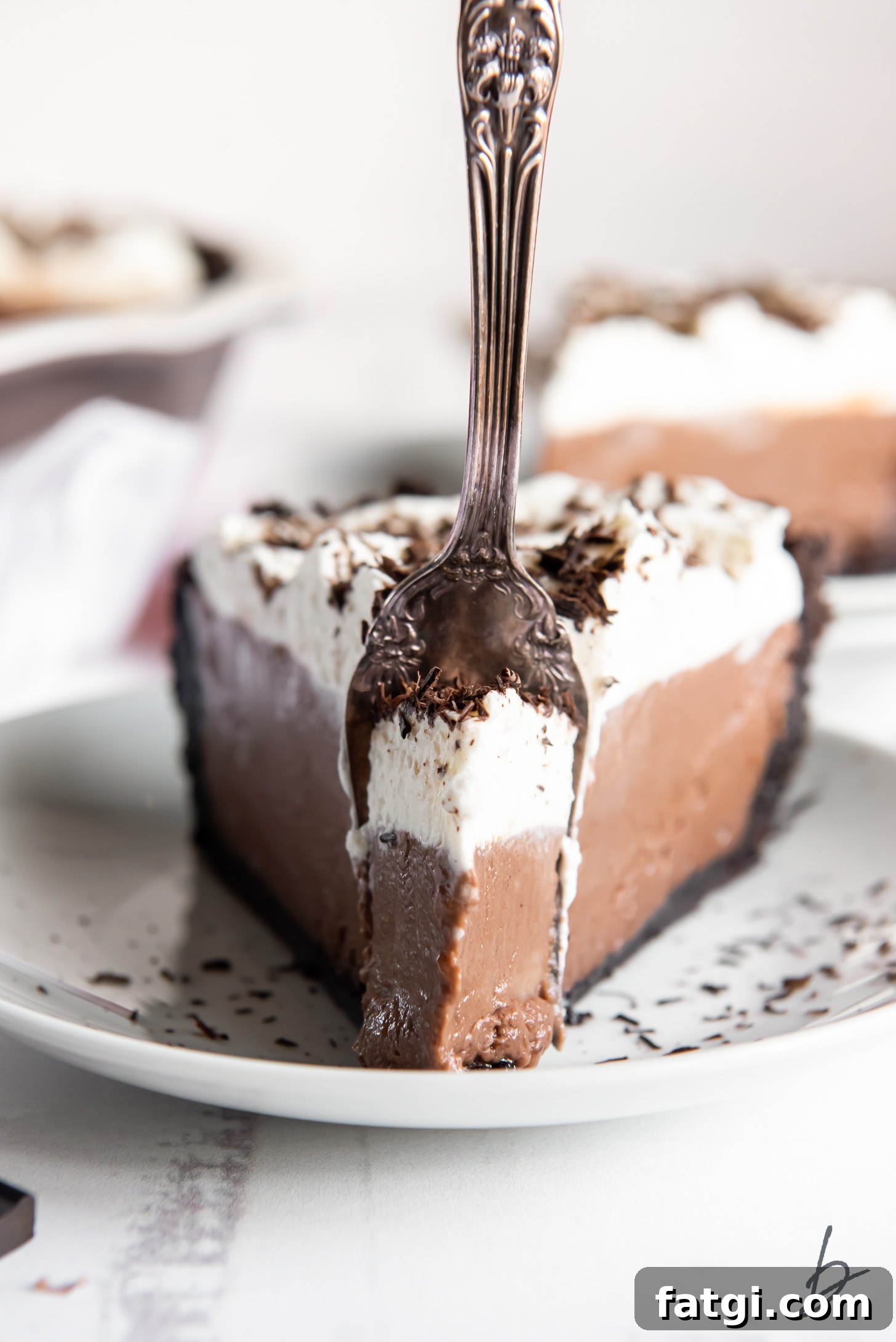 slice of chocolate cream pie with a fork stuck in the front standing upright