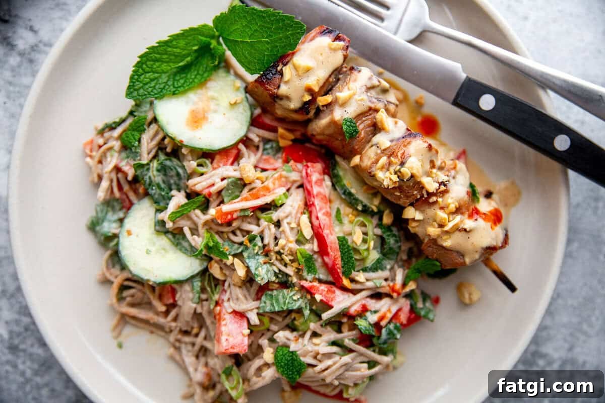 Juicy Marinated Pork Kebabs with Peanut Noodle Salad 10 Close-up of grilled pork kebabs on skewers with fresh herbs and salad