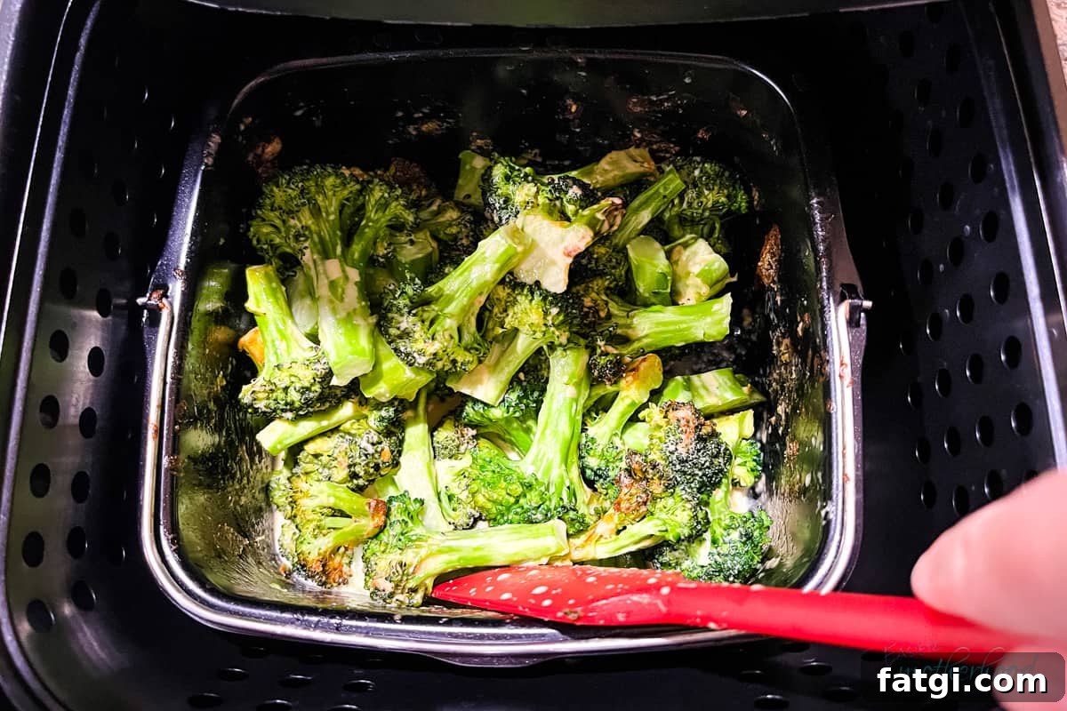Casserole dish inside air fryer with spatula stirring midway through cooking