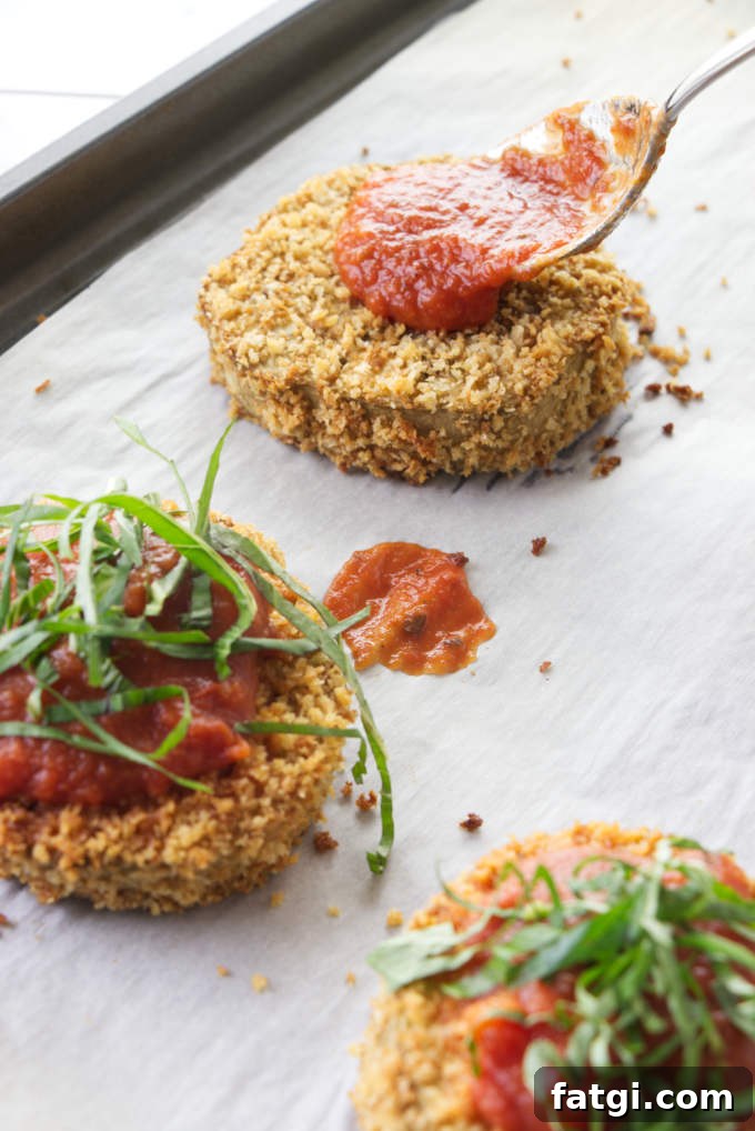 Adding marinara sauce to eggplant slices.