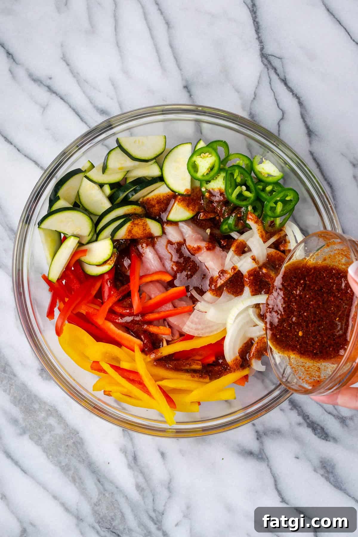 Sheet Pan Chicken Fajitas with Peppers and Onions 5 Chicken, bell peppers, onion, zucchini and jalapeno in a large bowl with fajitas marinade.
