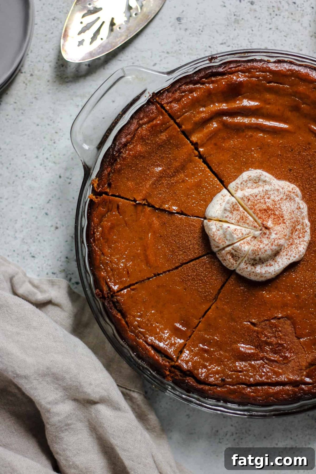 classic pumpkin pie with gingersnap cookie crust flatlay photo of a pumpkin pie with whipped cream and three cut slices