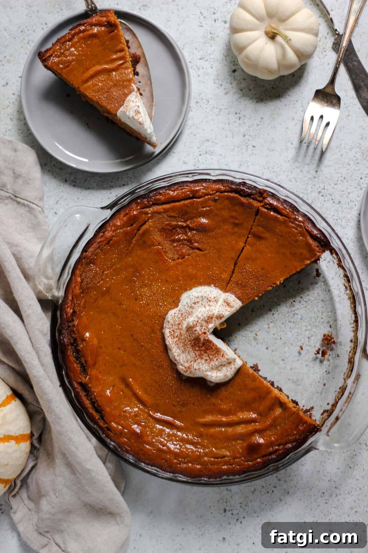 easy pumpkin pie with gingersnap crust flatlay of pumpkin pie in a round glass dish with a slice of pie on a small grey plate