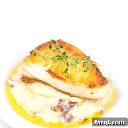 a plate of pan seared sea bass with mashed potatoes with a butter sauce and fresh herbs garnish