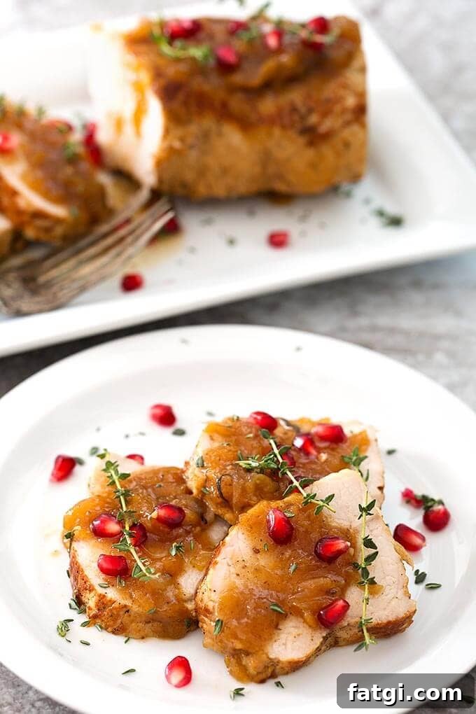 Instant Pot Pork Tenderloin with Balsamic Apples 3 Sliced Balsamic Apple Pork Tenderloin garnished with pomegranate and thyme on a white plate