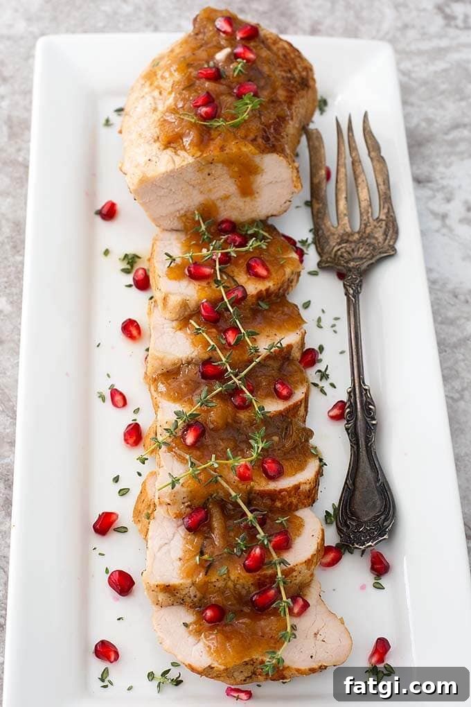 Instant Pot Pork Tenderloin with Balsamic Apples 5 Sliced Balsamic Apple Pork Tenderloin Balsamic Apple Pork Tenderloin garnished with pomegranate and thyme on a white plate