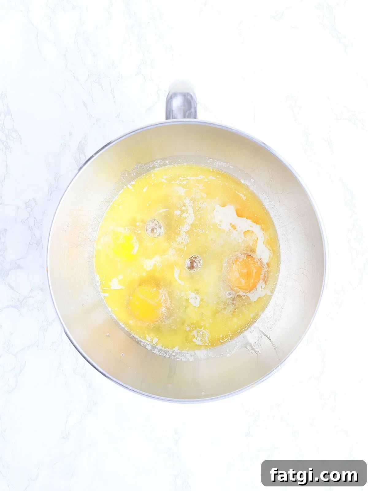 Eggs, melted butter, corn syrup, bourbon, brown sugar and vanilla unmixed in a metal mixing bowl.