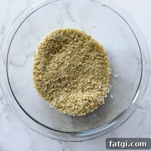 Breadcrumbs in a glass bowl mixed with parmesan cheese.