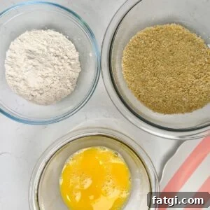 Three glass bowls, one with whisked eggs, one with flour and on with breadcrumbs.