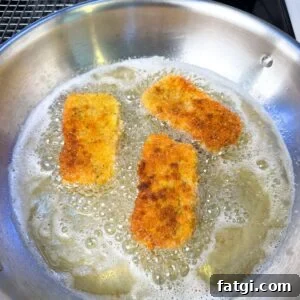 Mozzarella sticks frying in a pan.
