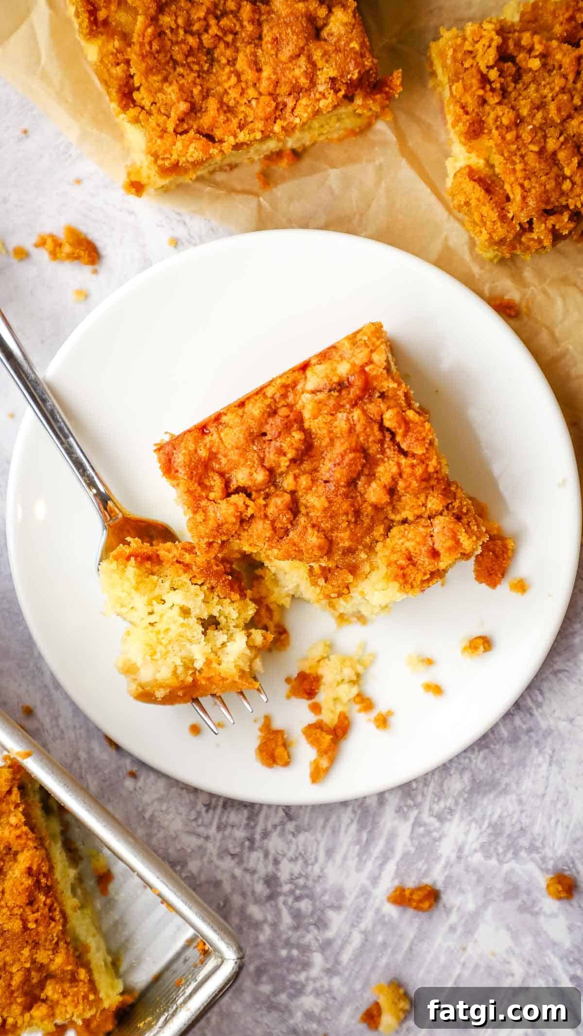 a plate with a square piece of cake with a spoon cutting a bite into it