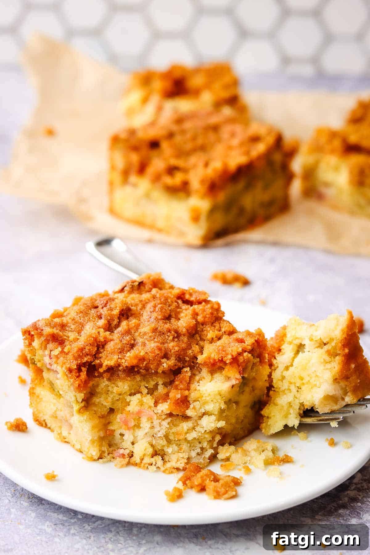 a slice of rhubarb coffee cake with a bite cut out with a fork