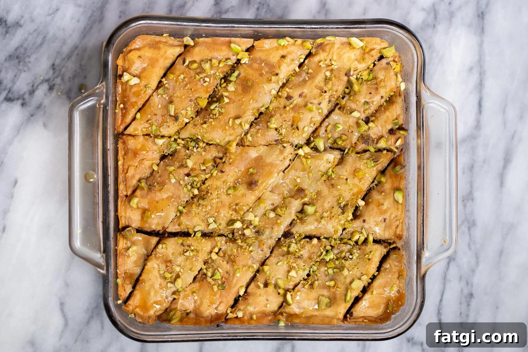 Vegan Baklava with Date and Nut Filling 18 baked vegan baklava being sprinkled with pistachios