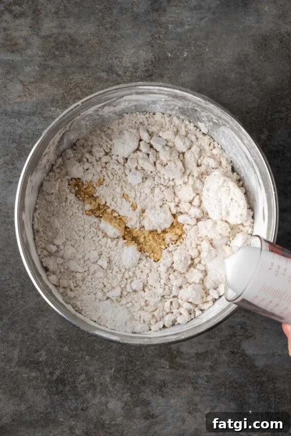 Milk added to frosting ingredients in a mixing bowl.