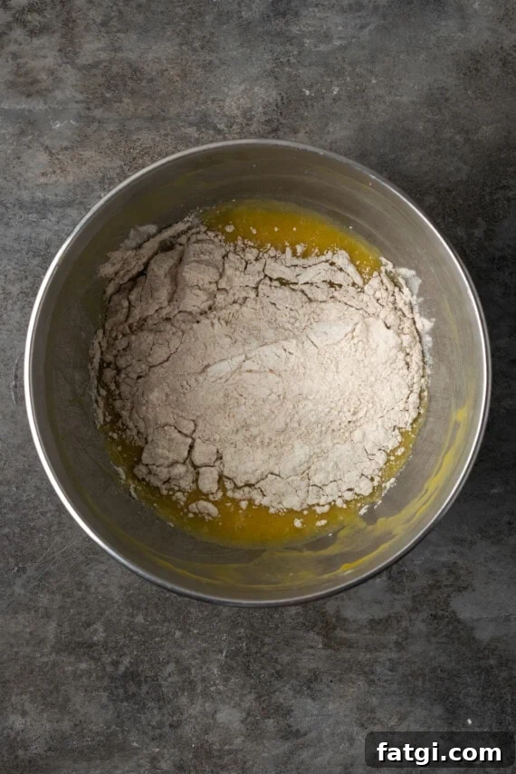 Dry ingredients added to wet cupcake batter in a mixing bowl.