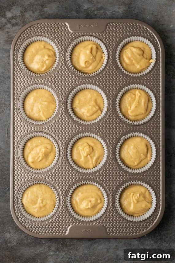 Overhead view of a lined metal cupake pan filled with snickerdoodle cupcake batter.