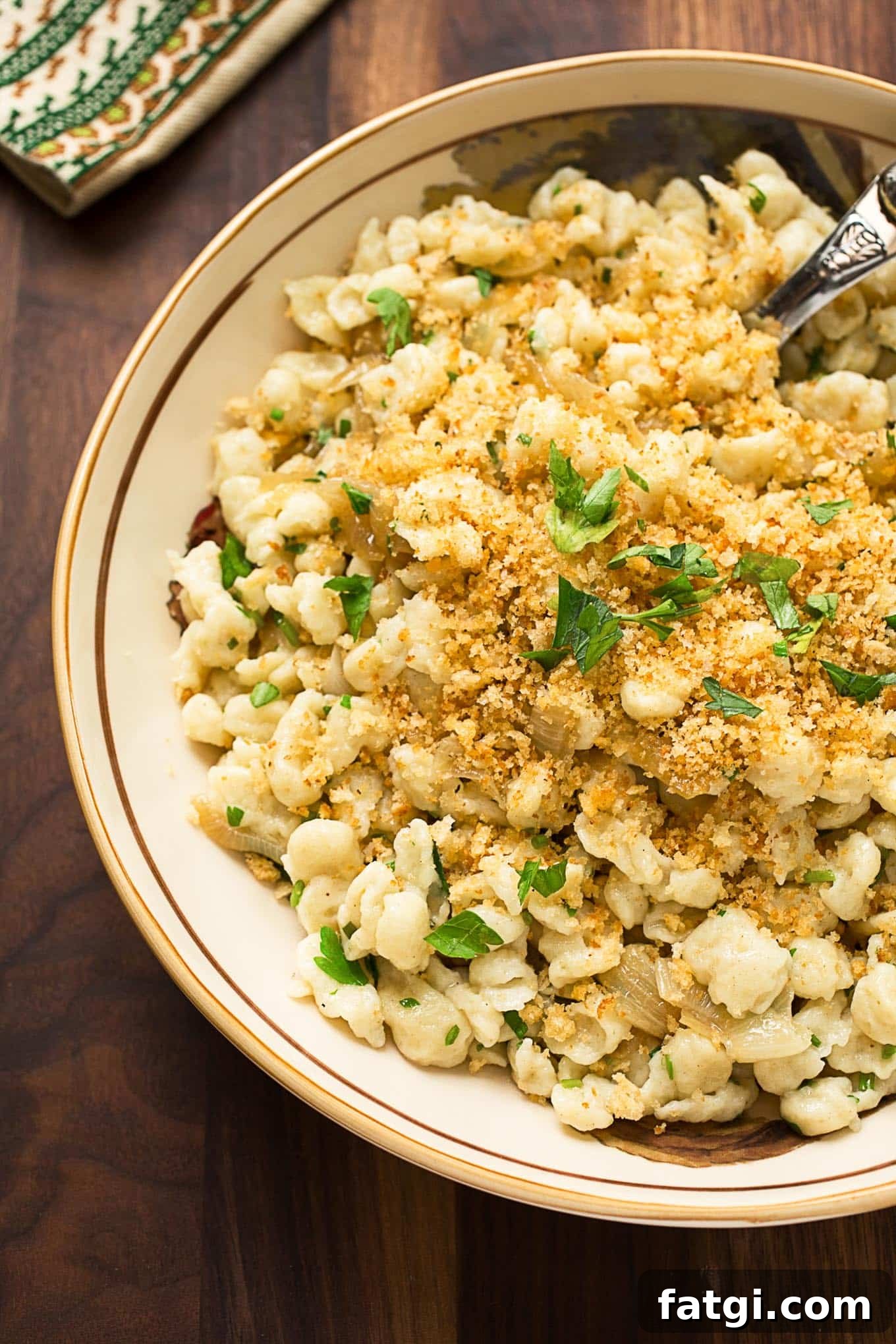Herbed Spaetzle with Caramelized Onions 2 spaetzle in an invory serving bowl garnished with bread crumbs and parsely