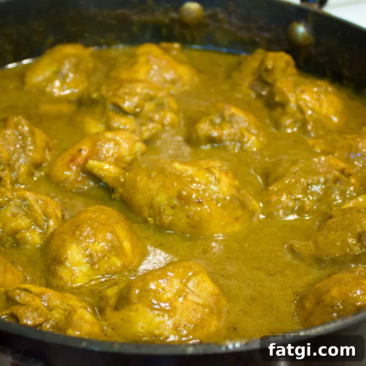 Curry chicken simmering in a skillet.